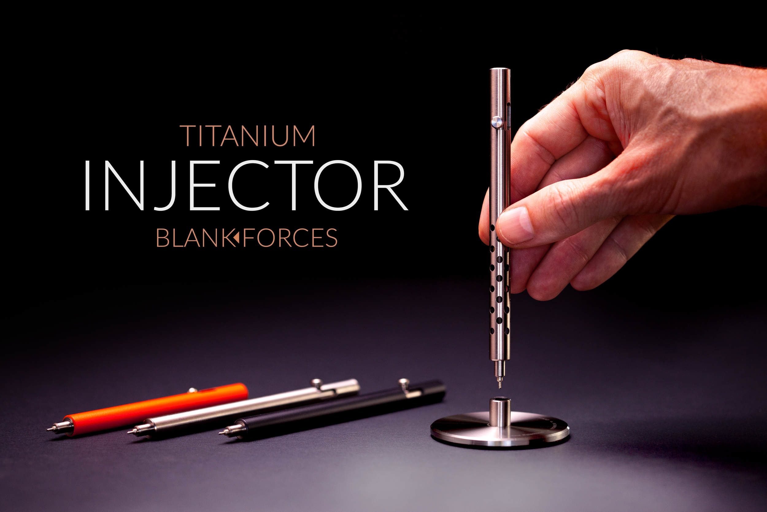 Putting the Silencer version of the Injector titanium bolt action pen into it's dock with other color options on table.