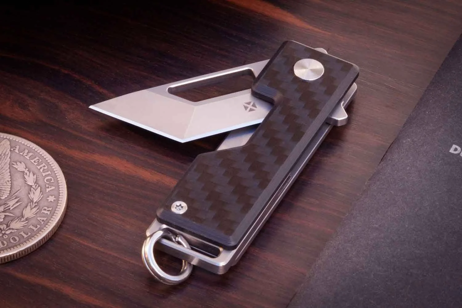 Carbon version of the Pocket Tanto EDC keychain knife with the blade partially open.