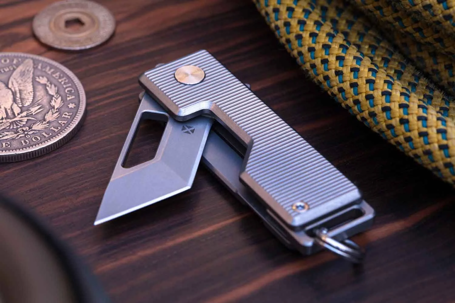 Vector version of the Pocket Tanto EDC Keychain knife with the blade partial open laying on wood table surface.