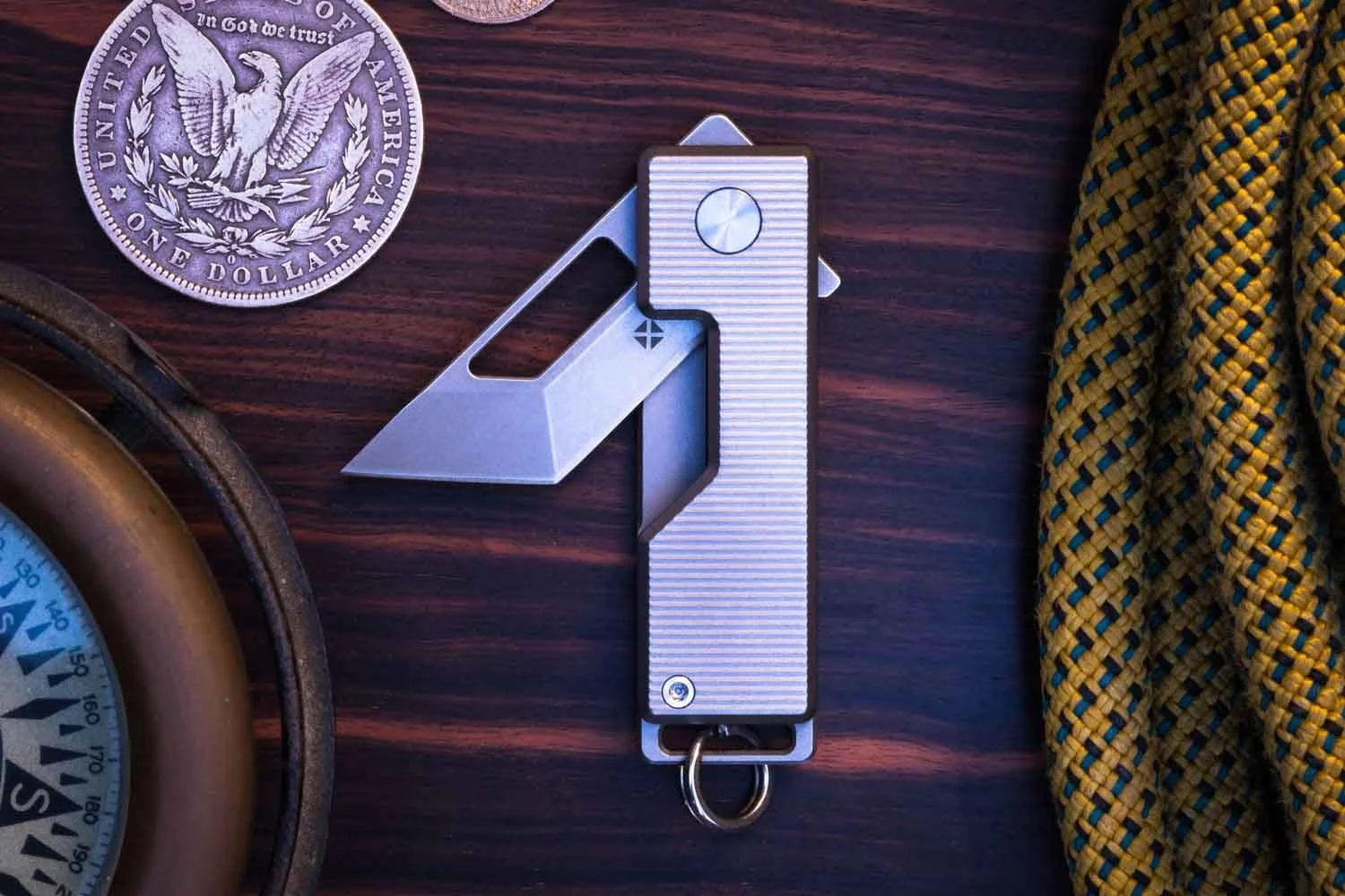 Vector version of the Pocket Tanto EDC Keychain knife with the blade partial open - next to silver dollar.