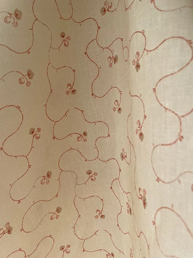 Close-up of Parlour Posy linen fabric in russet on eggshell, highlighting fine weave and delicate floral pattern.