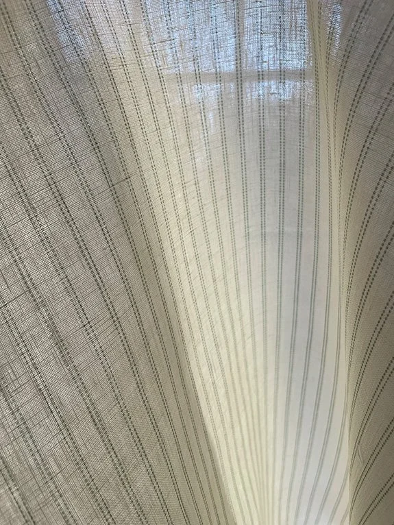 Play of light and shadow from window frame across the Pillow Stripe design in Lichen green