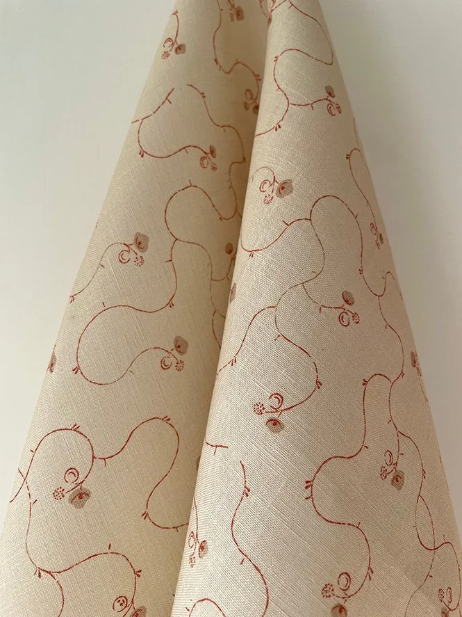 Parlour Posy linen fabric in russet on eggshell, beautifully draped to show soft texture and flowing floral pattern.