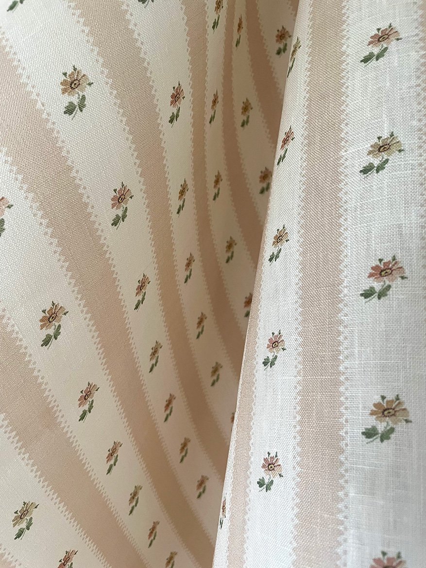 Close-up of Hat Box Stripe Plaster Pink midweight linen showing plaster pink candy stripes and small daisy sprigs.