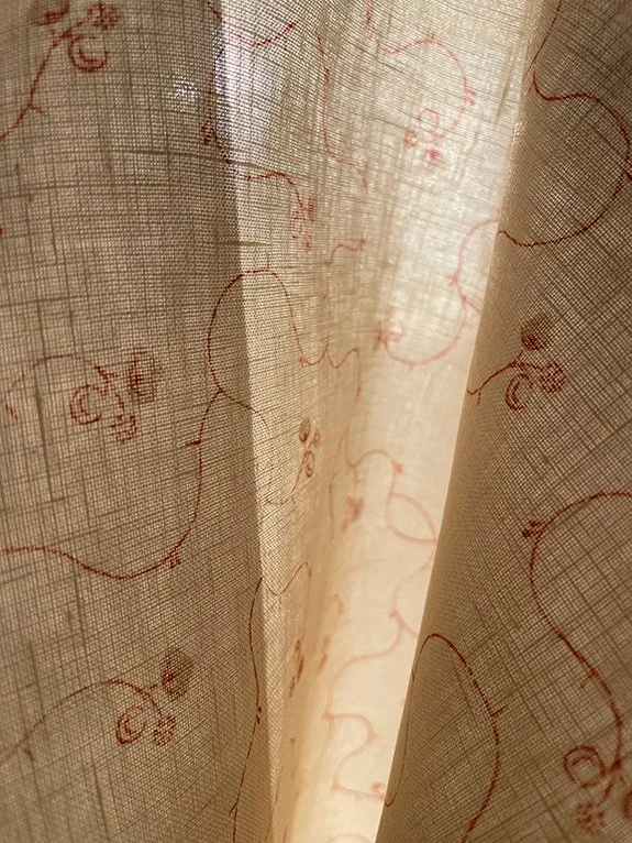 Parlour Posy linen in russet on eggshell shown against natural light, revealing its semi-sheer texture and gentle light filtering.