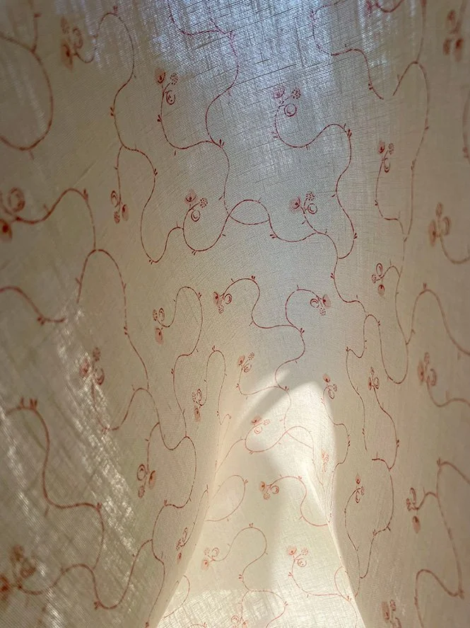 Parlour Posy Russet on Antique Cream midweight linen held to the light, showing subtle translucency and floral print.