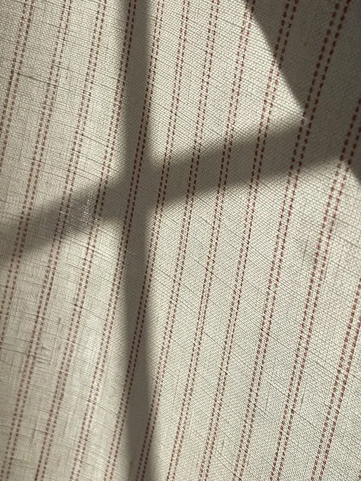 Soft window-lattice shadows falling over marsala pink Pillow stripe material for a natural light effect