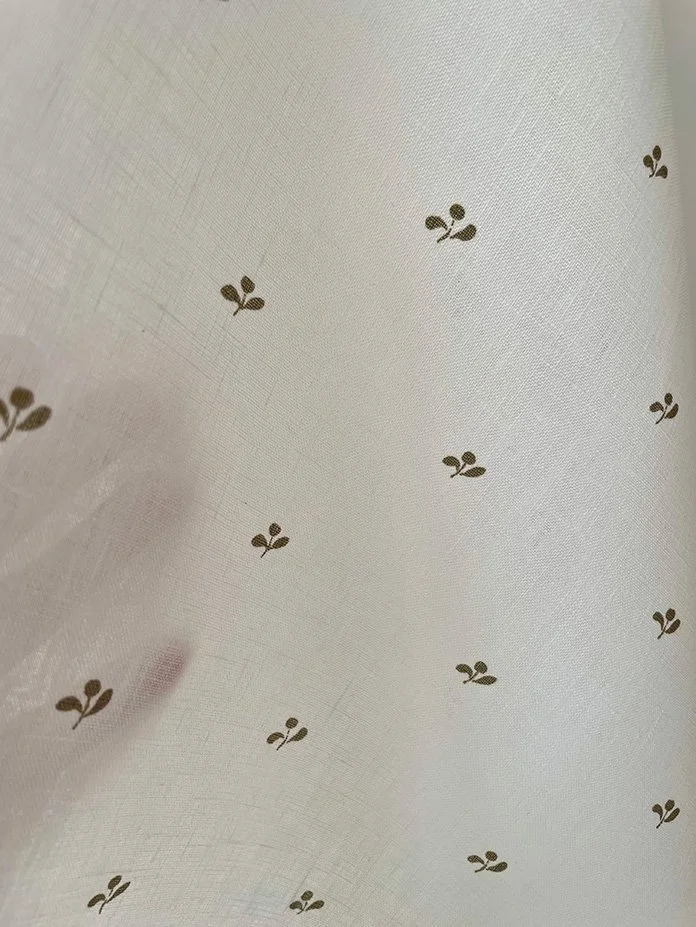 Lawn Flower khaki green fabric held with hand behind to reveal light filtering through.