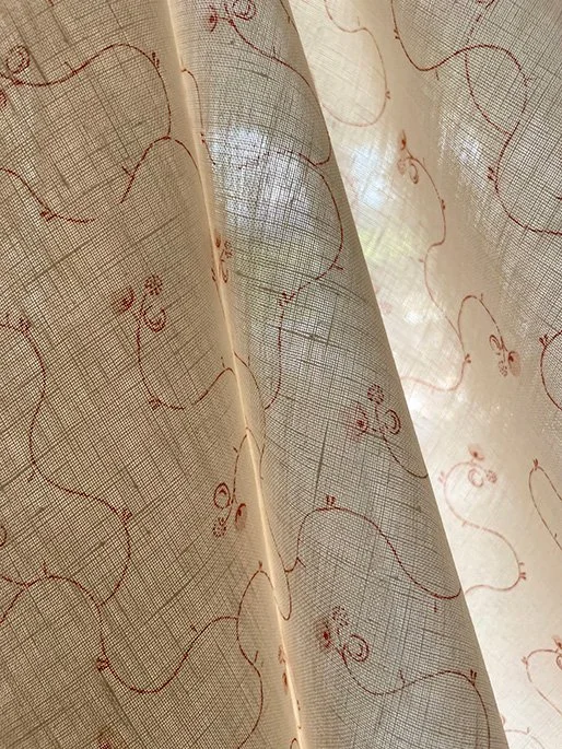Light filtering through Parlour Posy Russet on Antique Cream fabric, revealing weave, translucency and delicate flowers.