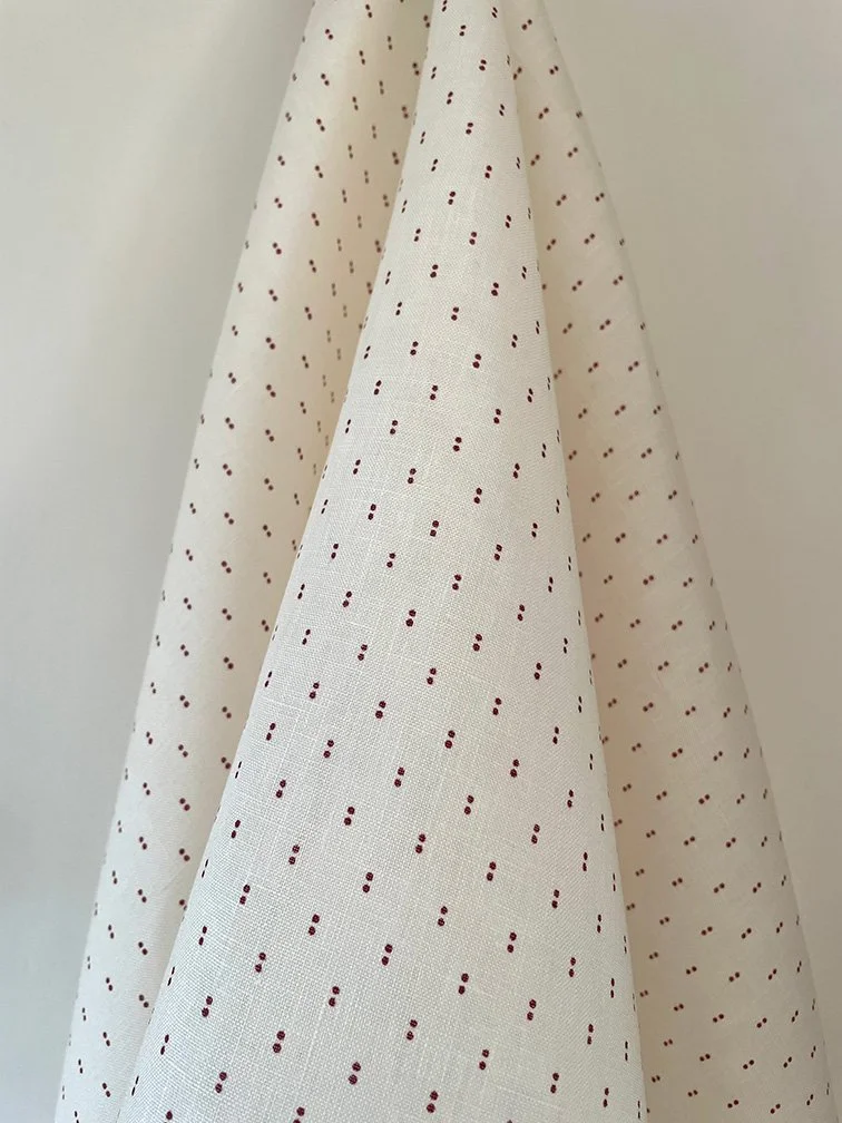 Petite Pair of Dots plum on cream fabric draped to highlight pattern spacing and movement.