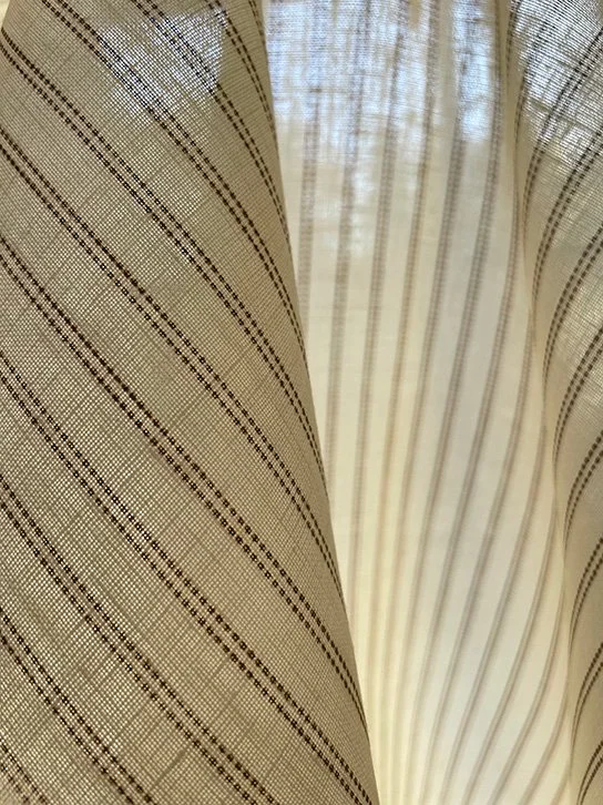Pillow Stripe fabric in saddle brown photographed against a window to show light filtering and translucency