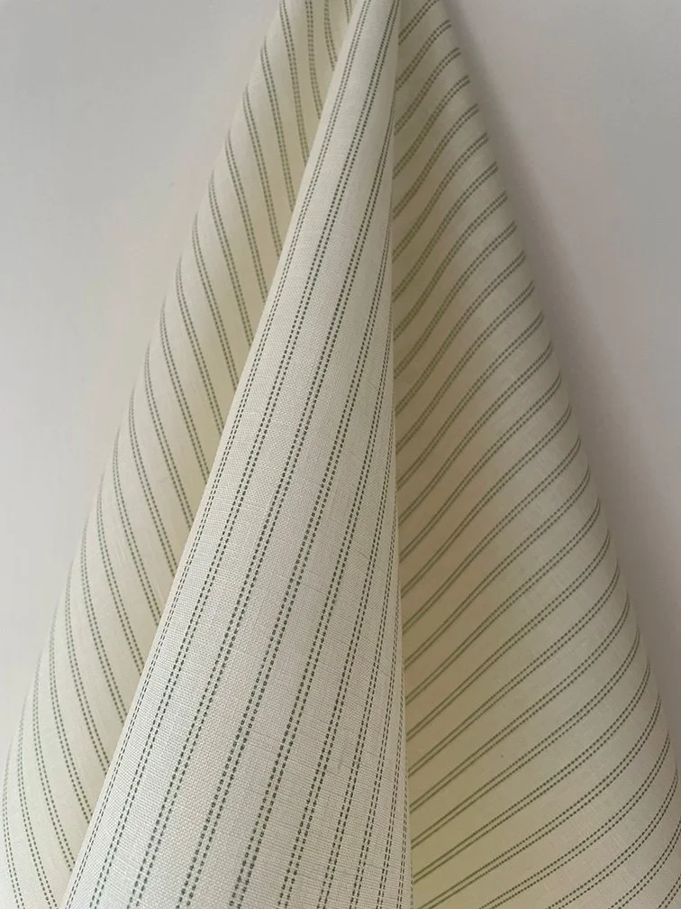 Pillow stripe material in Lichen green flowing in a natural drape to highlight movement and hand-feel.