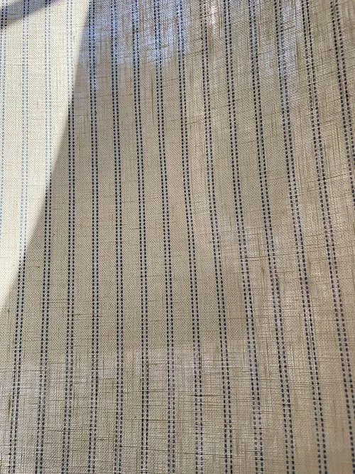 Pillow stripe fabric in cornflower blue photographed against a window to show light filtering and translucency.