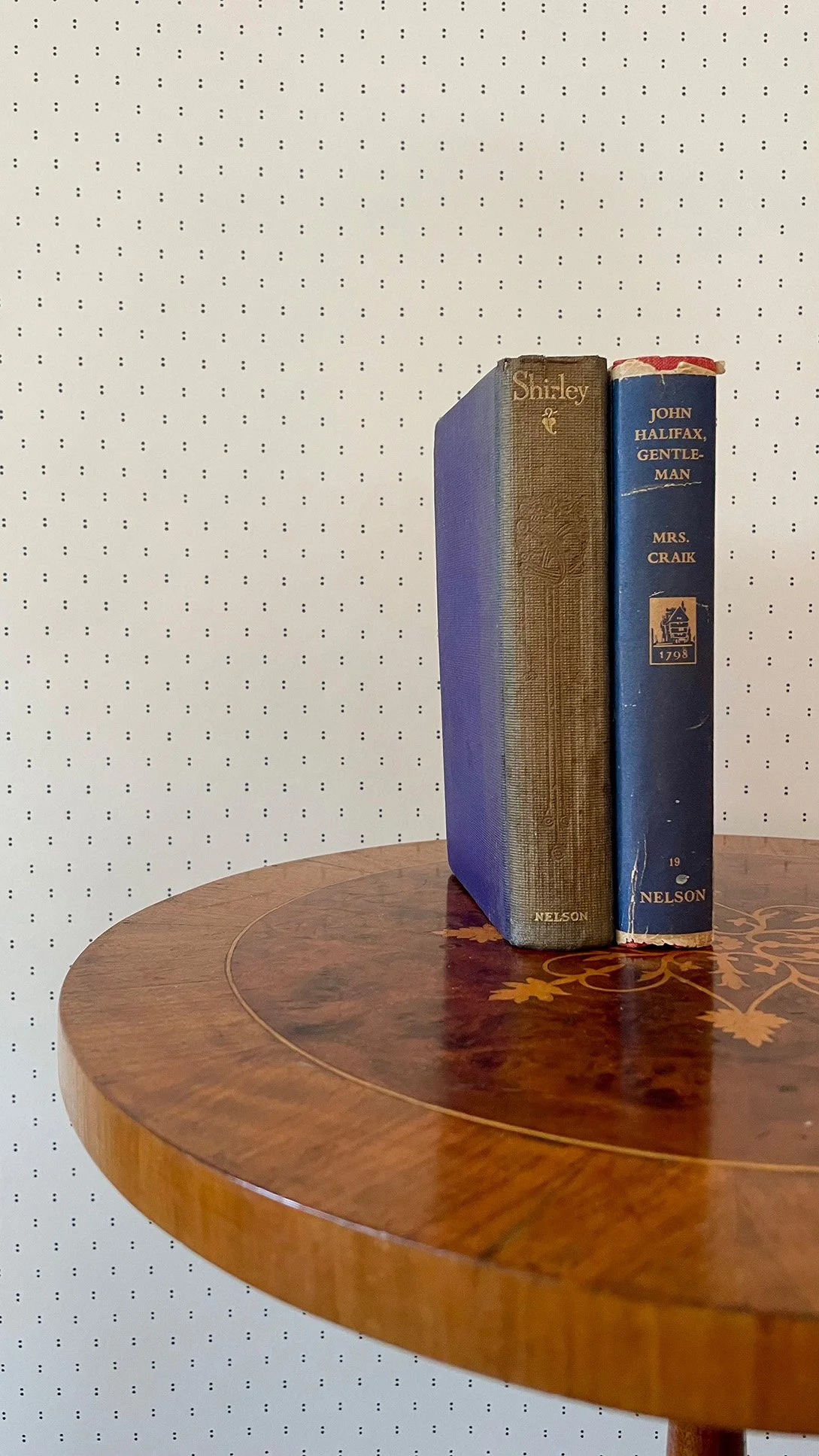 Pair of Dots Ironstone Blue on cream wallpaper sample shown with blue radio on round wooden table.