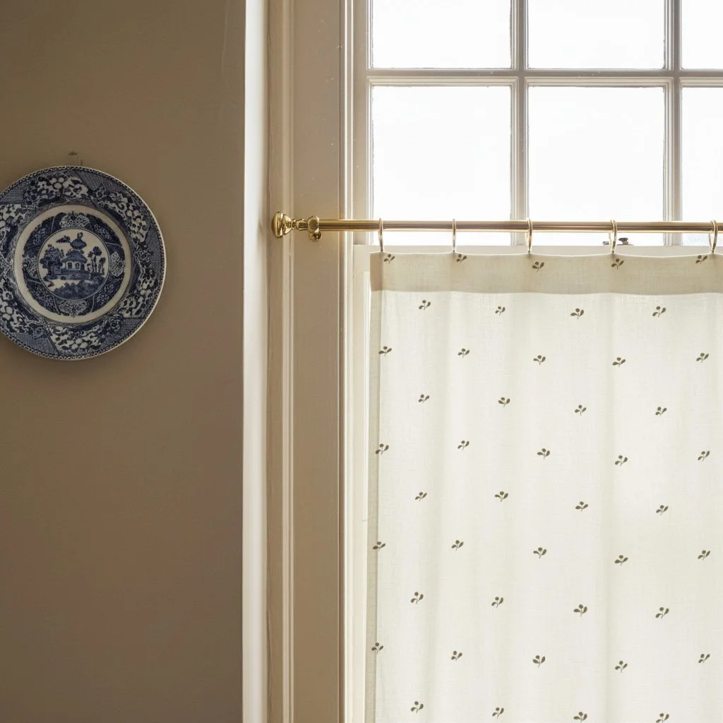 Khaki green Lawn Flower café curtains on interior sash window, adding patterned softness.