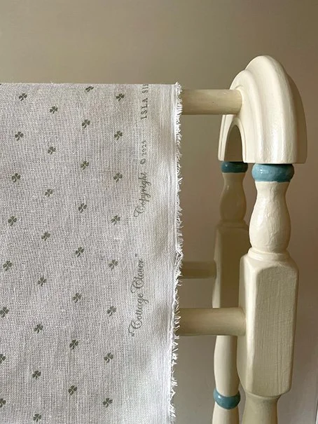 Close-up of Cottage Clover sheer linen fabric in Lichen green draped over an antique drying rack..