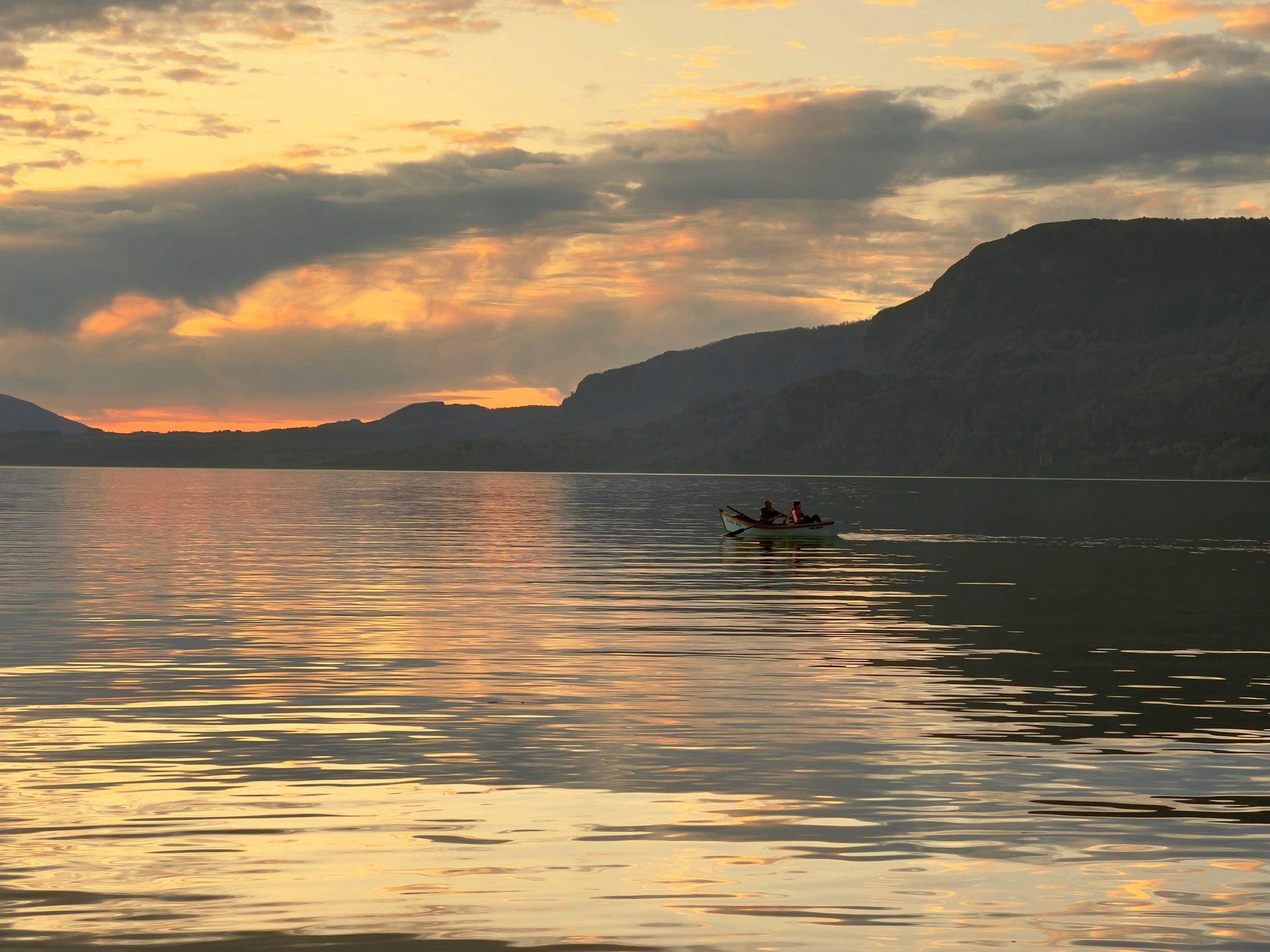 Kayakers paddling on a calm mountain lake at sunrise