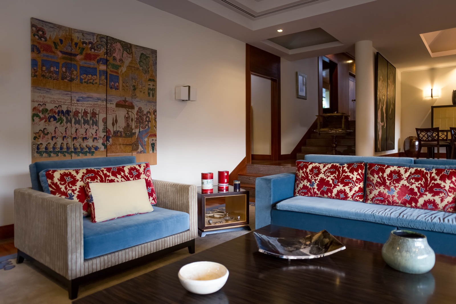 Sala de estar eclética com biombo ilustrado da Birmânia e estofos em veludo com padrões