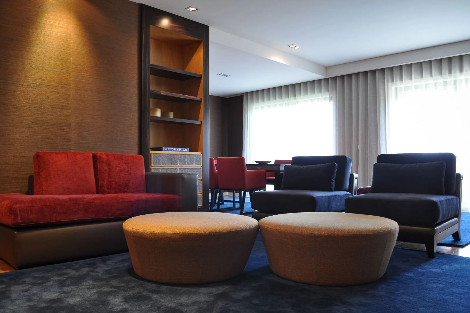 Modern and bold living area interior design with red and blue velvet sofas and poufs