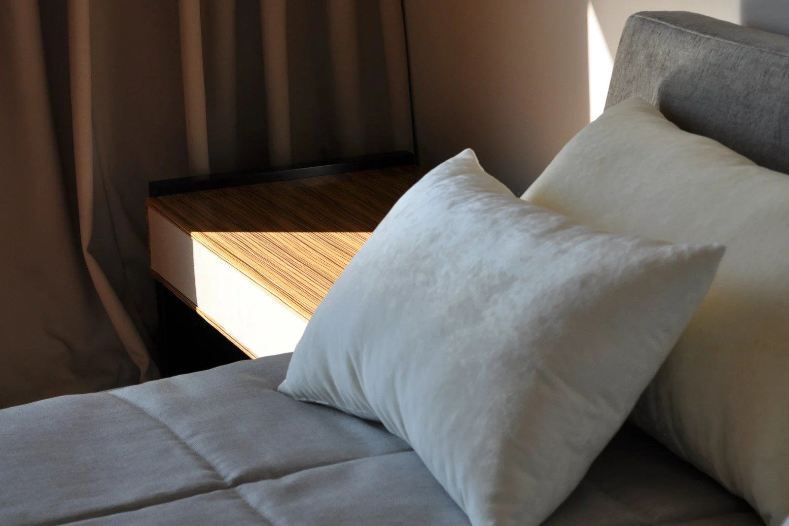 Neutral toned upholstery, bedcover, and white velvet pillows