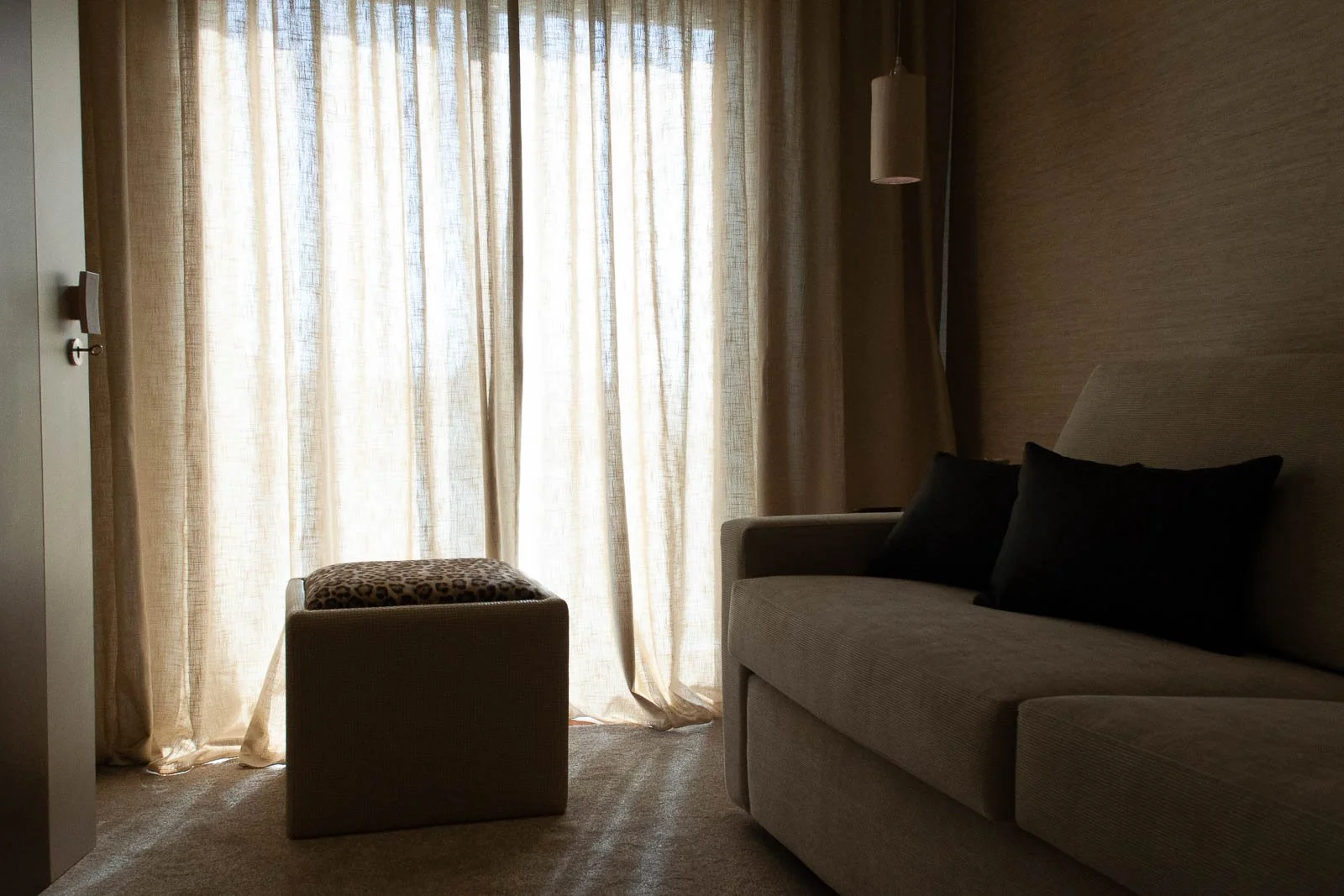 Light airy voile curtains in living room with leopard print upholstered pouf