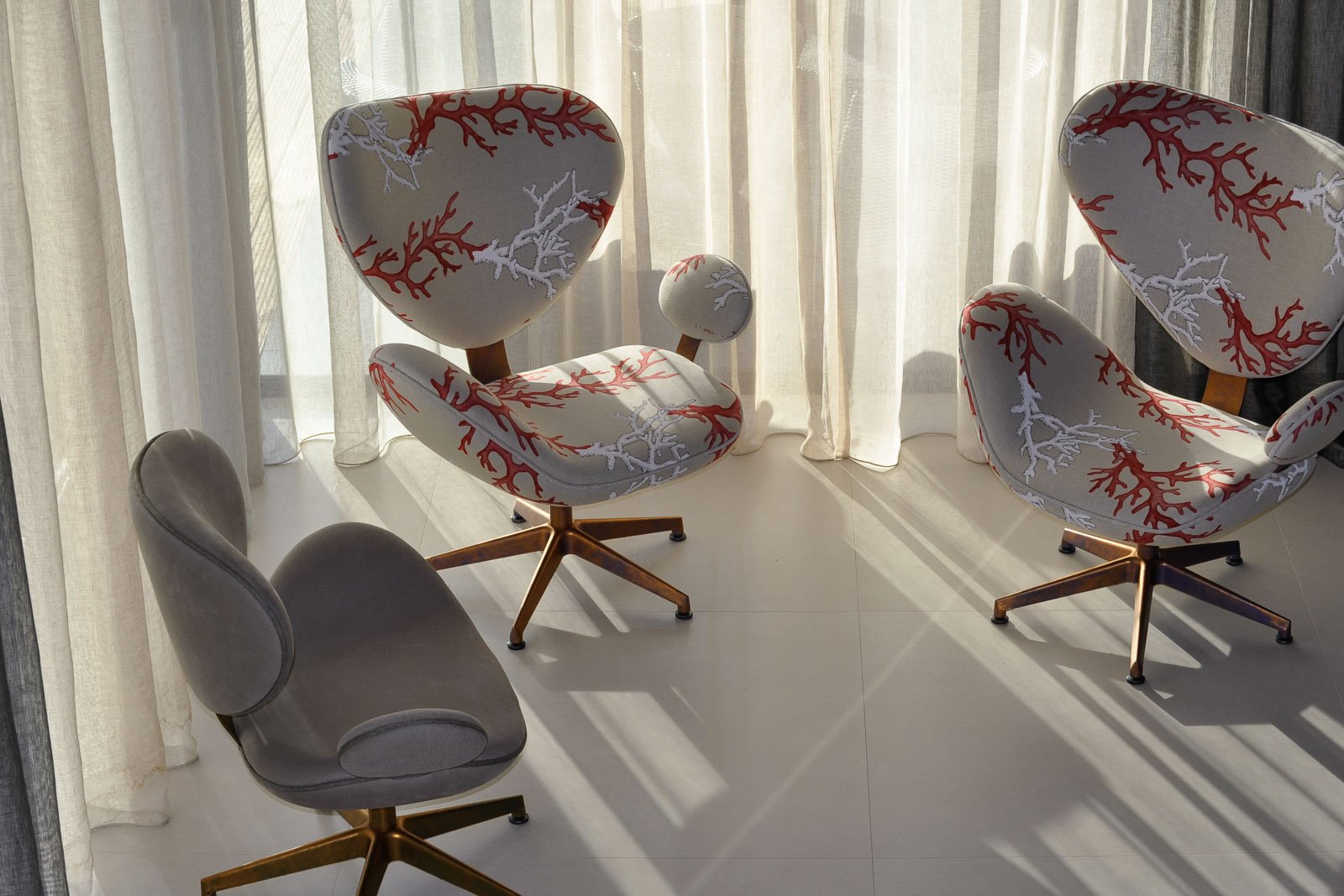 Light-filtering voile curtains and coral print design upholstery on office chairs