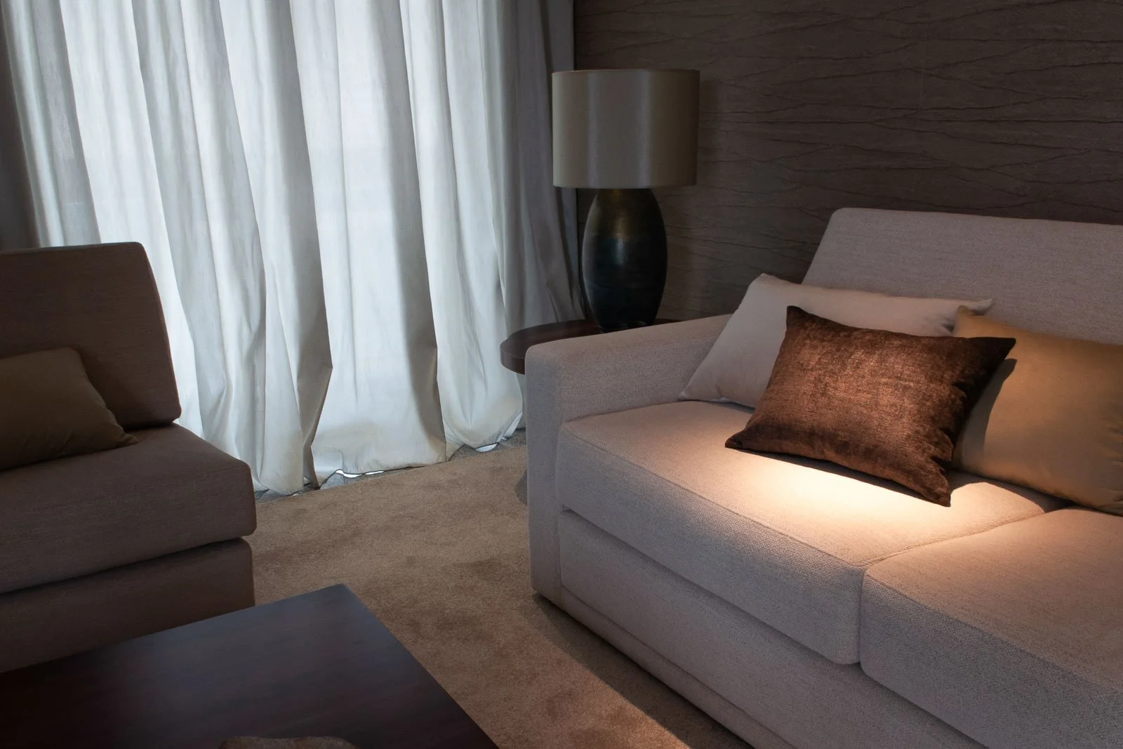 Serene living room with white voile curtains and white upholstered sofa, velvet pillows