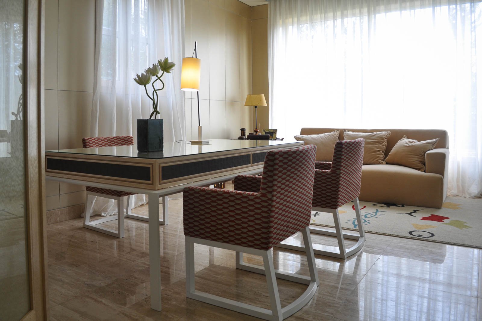 Soft toned living area with custom flooring, wallcoverings, dining table, patterned chairs and author-designed rug