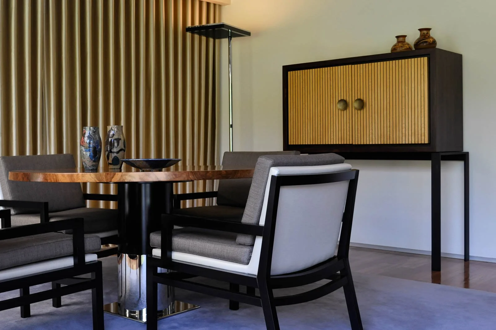 Sala de estar sofisticada com mesa, poltronas e aparador de autor, iluminação e têxteis selecionados
