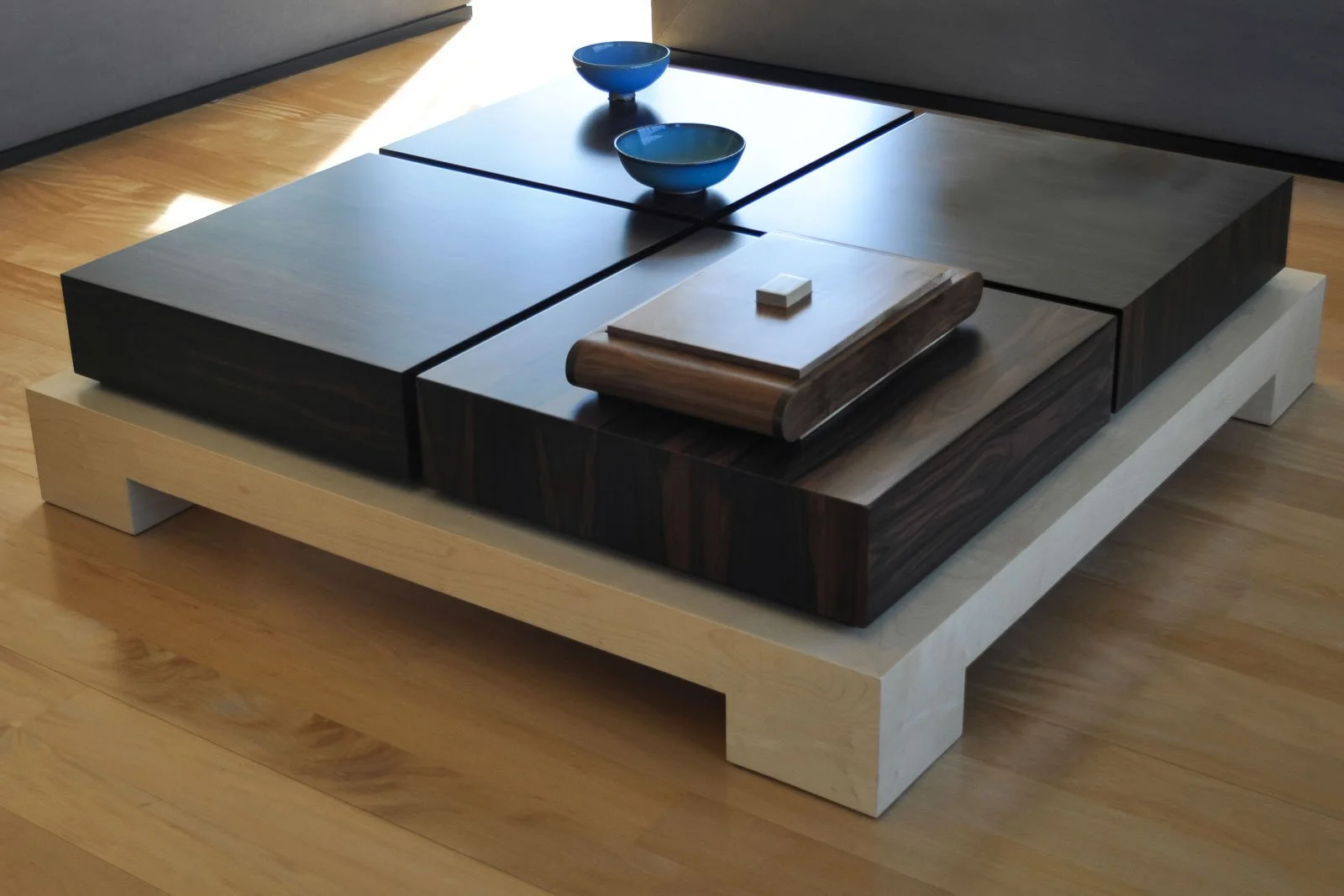 Mesa central refinada, com tampo em ébano de Macassar com secções, e pés quadrados em sicómoro