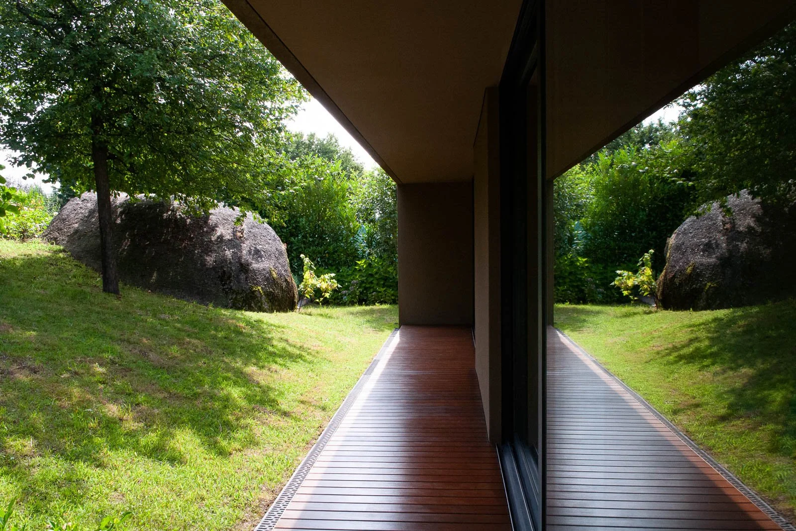 Detalhe arquitetónico do deck lateral da sala de estar com janelas para o jardim