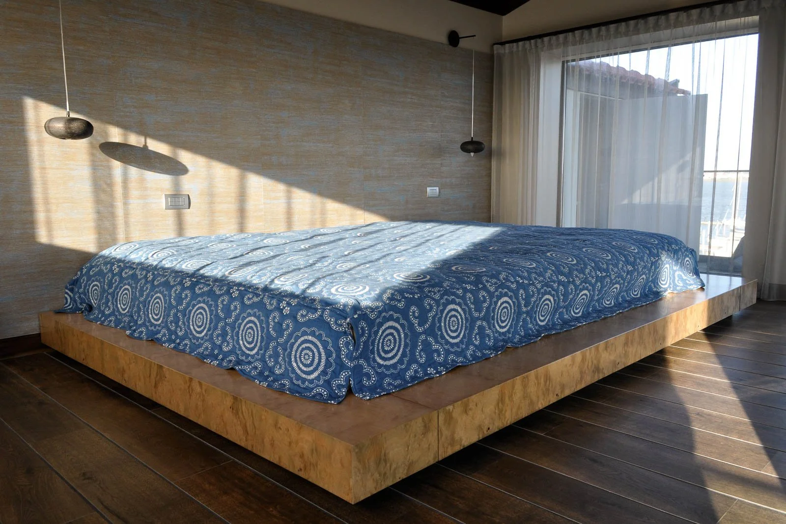 Capa de cama azul e branca com padrões bordados, em cama em raíz de mirto
