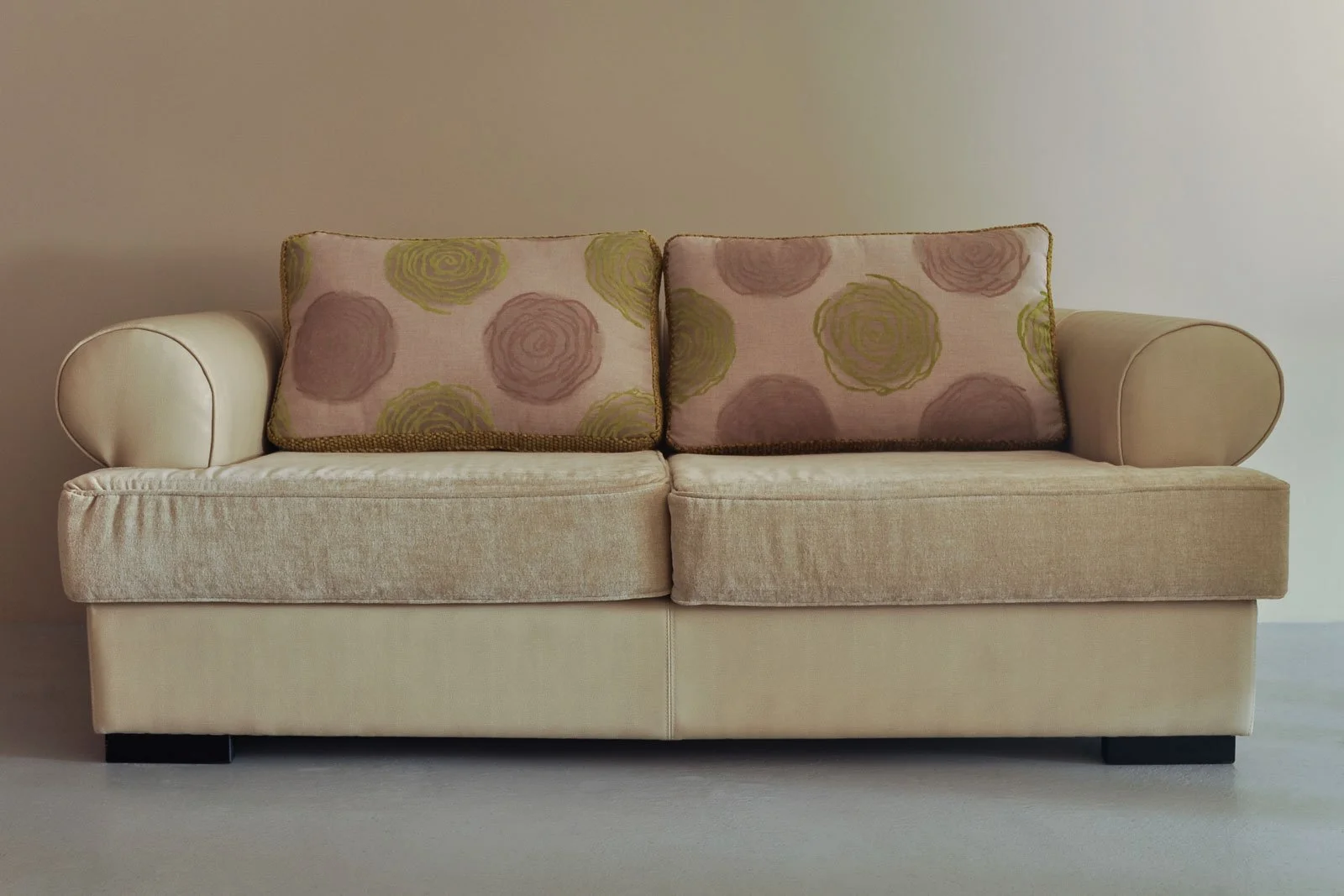 Sofá em pele clara com estofos e almofadas bordadas