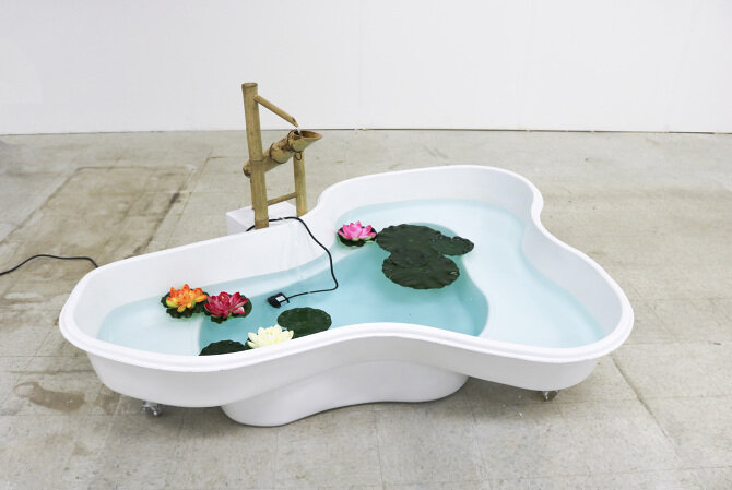   The Bath  preformed pond liner, shishi-odoshi, MDF, water, pond dye, artificial lotus flowers and leaves, polyester resin, enamel, 2018 