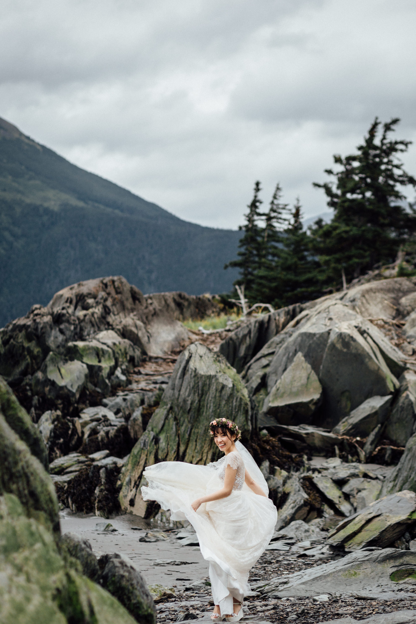 Bride twirling dress on rocky Alaskan beach