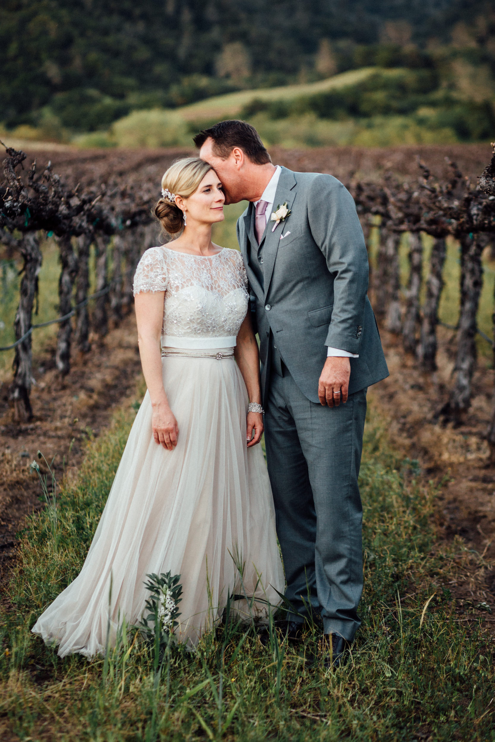 Groom whispering to bride in vineyard