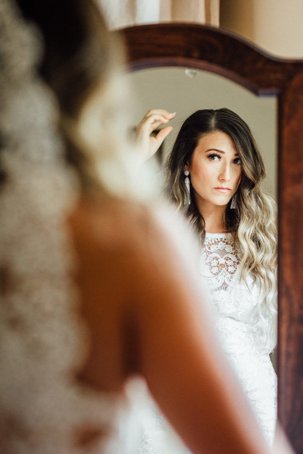Bride looking in mirror and fixing hair 