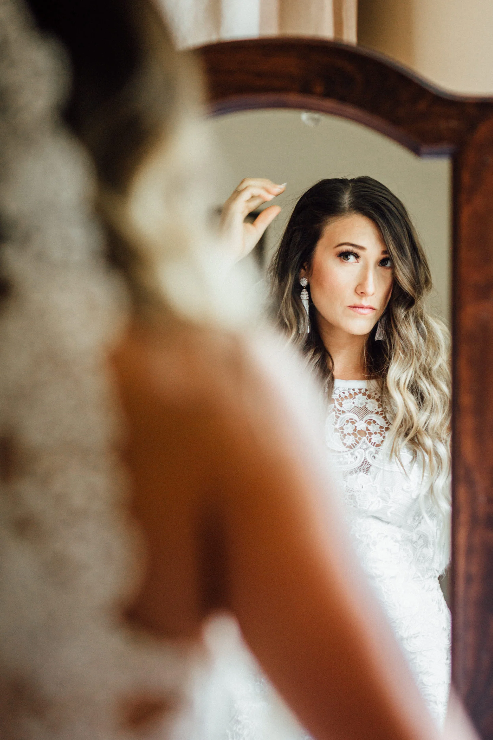 Bride looking in mirror and fixing hair