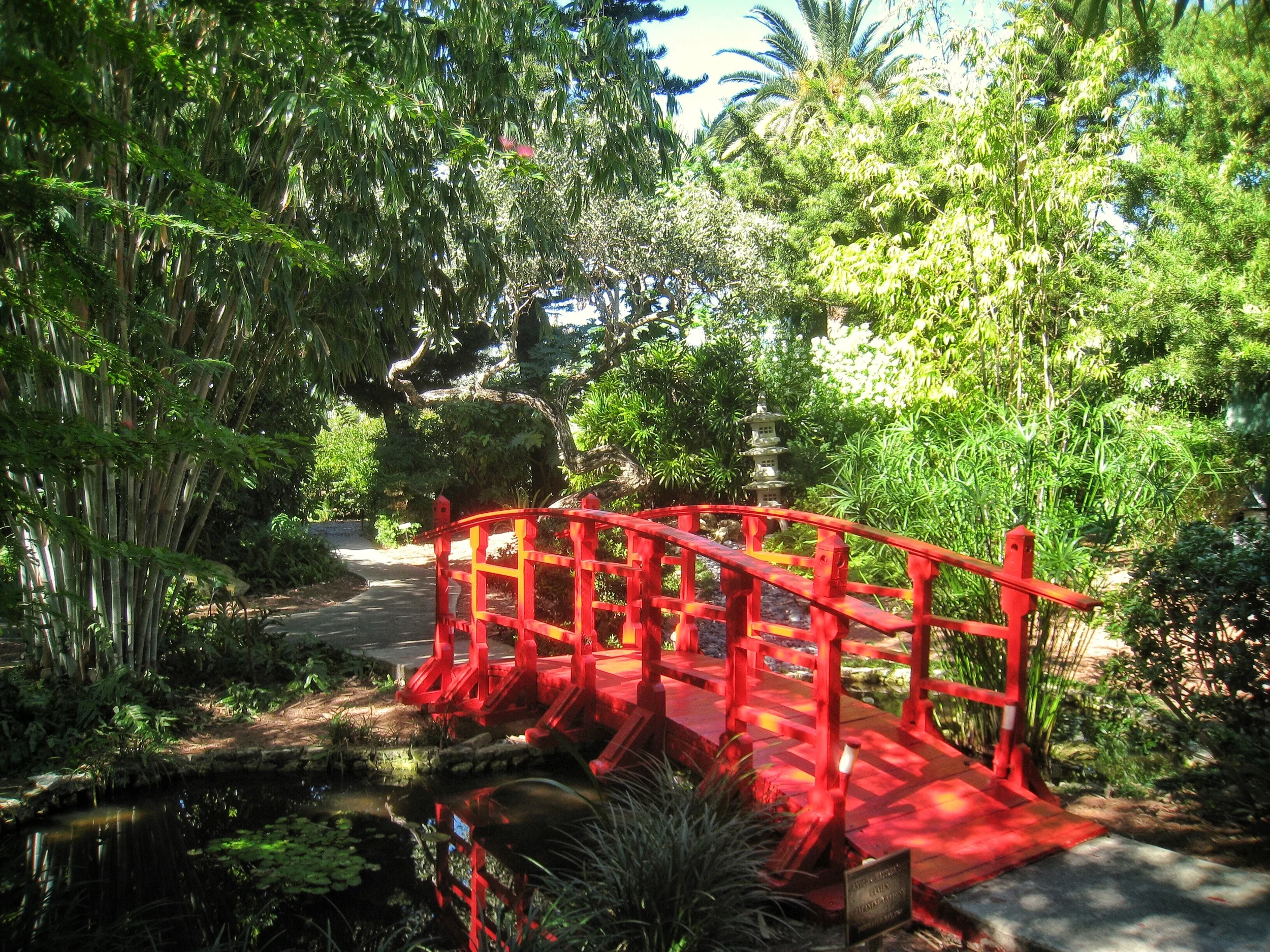 A bright red bridge crosses over the small pond in the Japanese Garden at the Miami Beach Botanical Garden, a private, serene setting for photography and events.