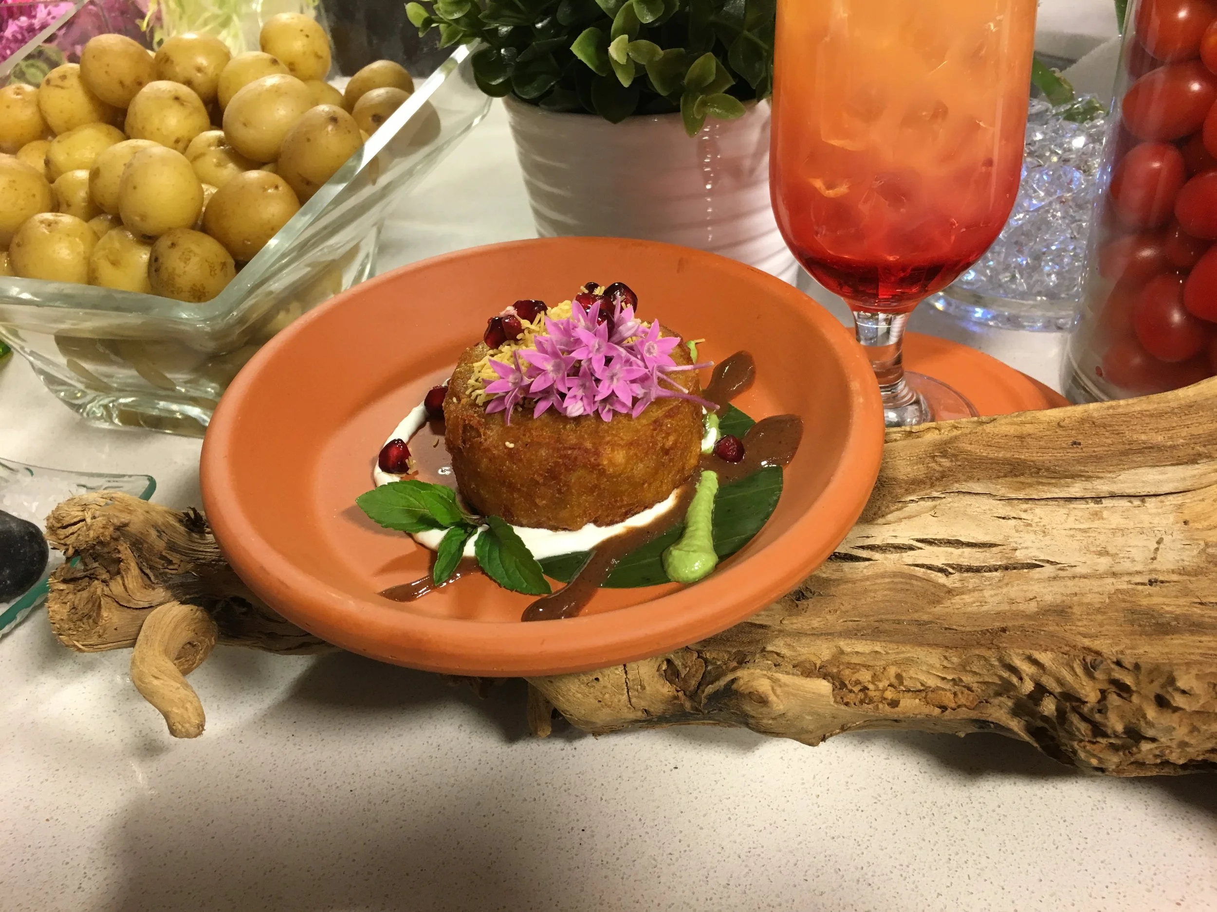 Aloo Tikki: potato cake with chat marsala and turmeric - tamarind sauce, mint sauce, yogurt sauce, garnished with crispy lentil threads and pomegranate.