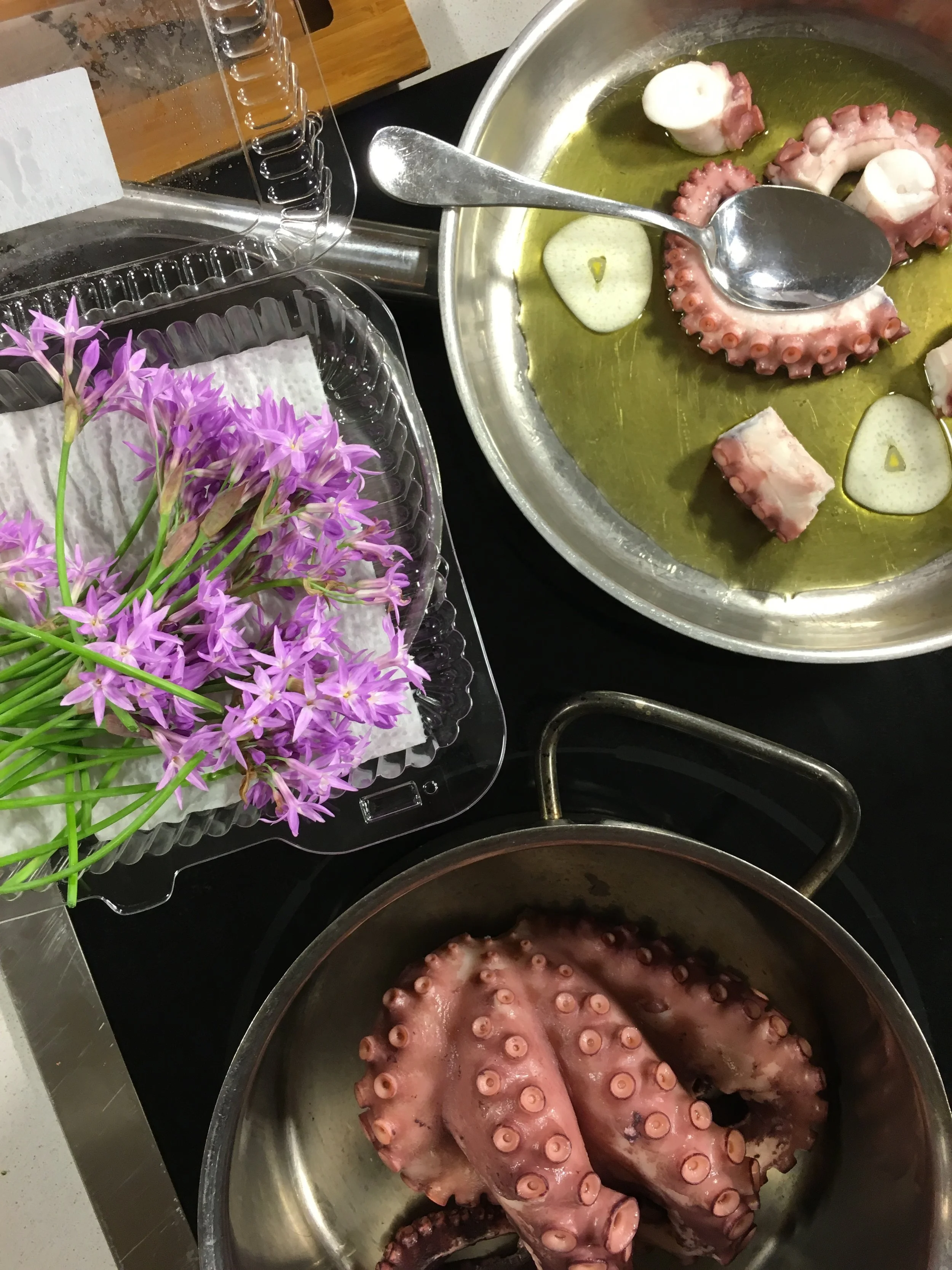 Prepping the "Pulpo A La Galega Moderne:" Tender poached octopus in garlic - served with potato river rock stone, brava sauce emulsion, Spanish olive oil and smoked paprika, garnished with garlic flower blossoms.