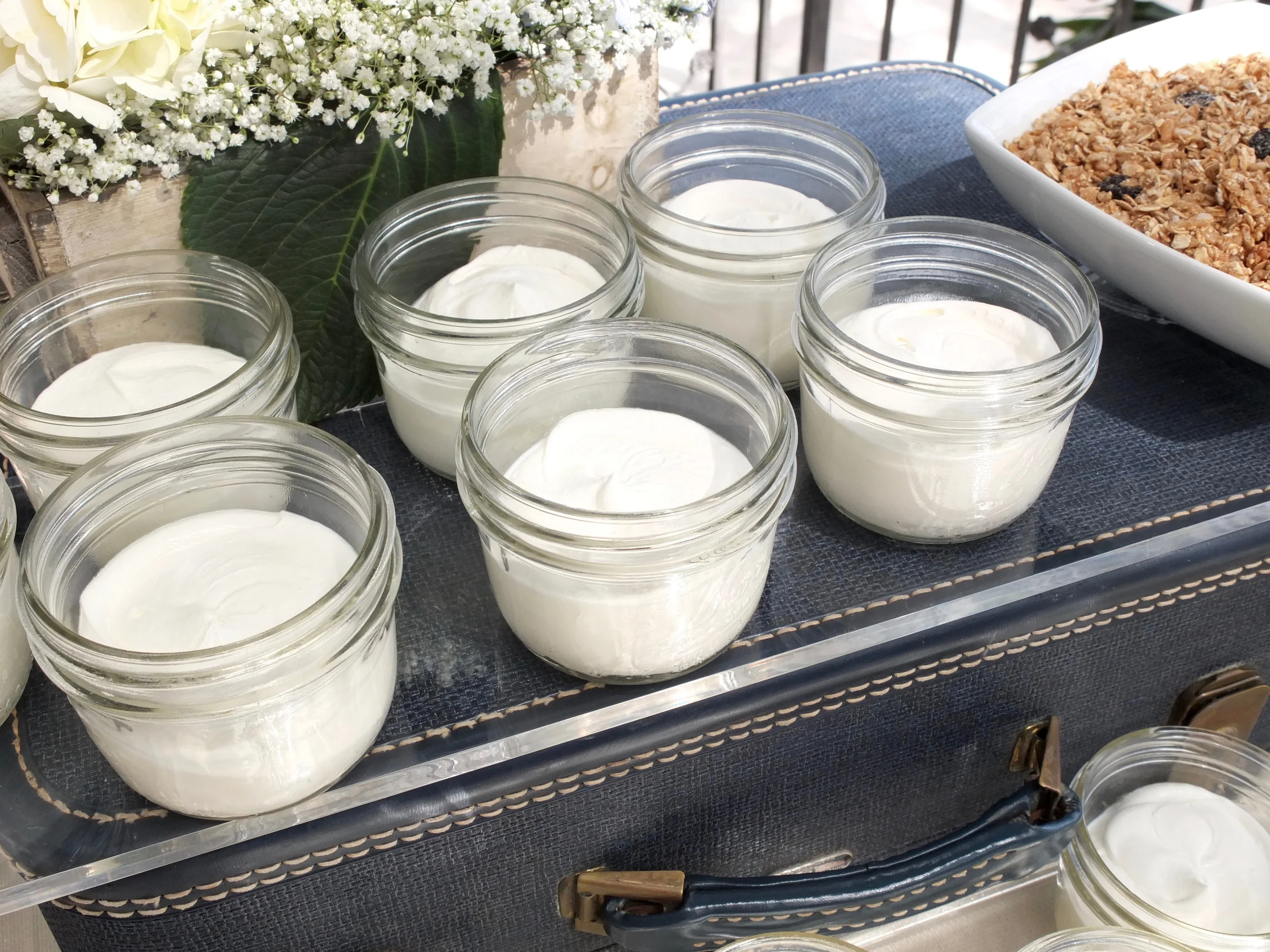 Mason Jar Yogurt Parfaits with Sides of Granola and Seasonal Fresh Fruit were displayed on antique luggage from Unearthed Vintage's collection.