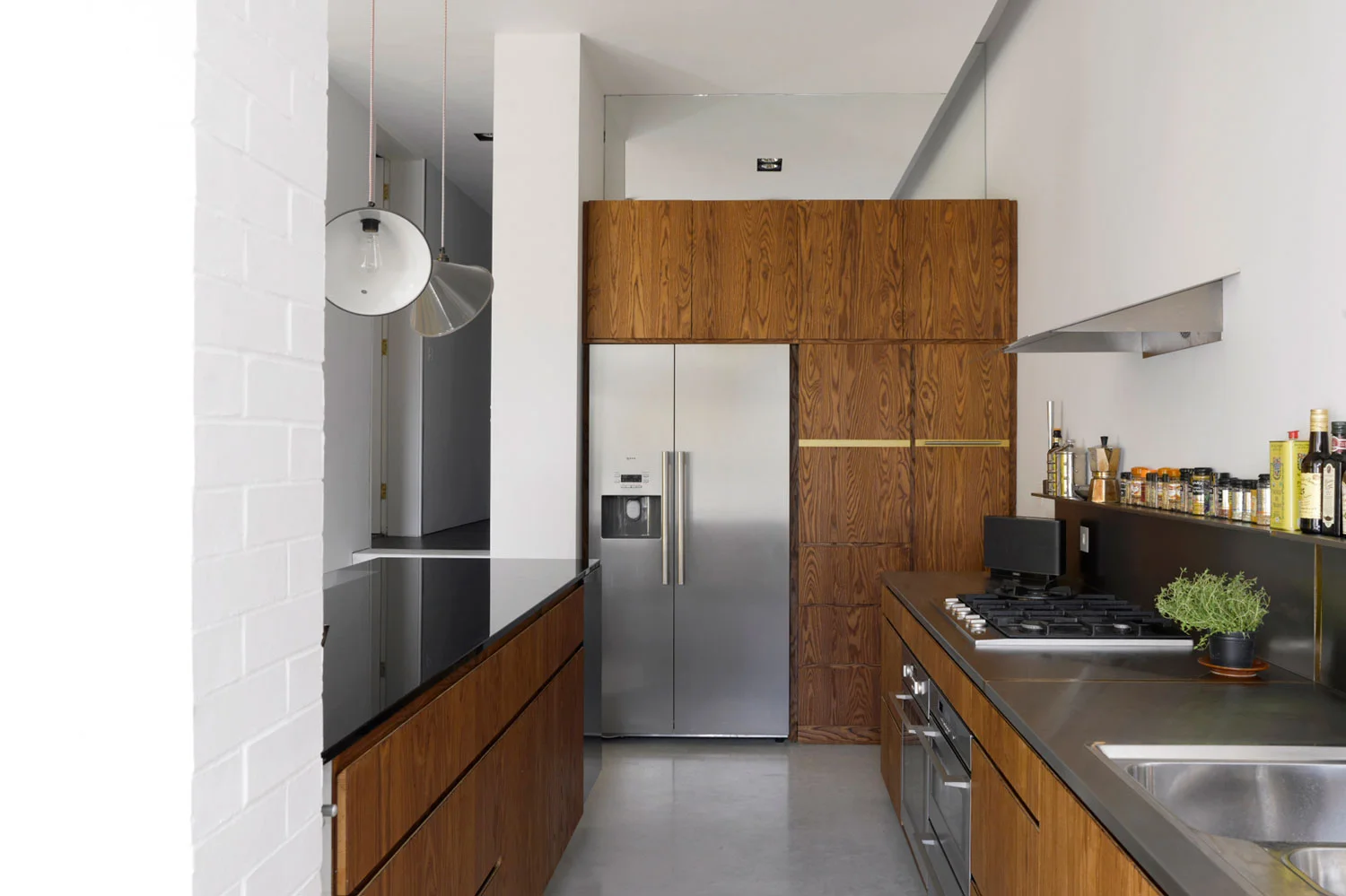 Our clients live in a 1930s house in Balham with their two young sons. One half of the couple had been raised in a modernist house in Belgium, surrounded by a collection of 20th Century Art while the other grew up in a mountainous region of Switzerland. Their sensibilities led them to give Liddicoat & Goldhill an open brief to adapt and expand their home, which had already been ‘opened up’ at ground floor level by previous architects. Liddicoat & Goldhill’s response addressed the entire house, and was based on analysis of the family’s living patterns, and by making only the most economical structural changes. The interior layout was fully remodelled, with the most invasive and dramatic work happening at ground floor level and in the cramped circulation space, where an efficient and sinuous new staircase was added. Selective re-instatement of previously-demolished walls reinstated the formal drawing room, facing the street, while a stepped extension to the rear created an open plan eating, cooking and informal relaxation area. The first floor was re-arranged to create a guest room, study and luxurious master suite with a meandering route from the sleeping area into the dressing and bathroom spaces. By extending at roof level, we created two new children bedrooms suites. These were designed to overlap the different functions of sleeping, entertaining and studying. The rooms have large structural glazed windows with integrated desks affording panoramic views across SW London. Aesthetically, the project has been conceived as a collage; a deliberate response to the vogue for monochromatic interiors. A rich mix of strongly-contrasting colours and textures creates a warmly tactile environment. In the kitchen, rough painted brickwork meets crisp plasterwork, black glass, stainless steel and strongly-grained wood. These provide the backdrop to carefully-chosen pieces of contemporary and mid-century Danish furniture, set against heated polished concrete floors. Key to the design was the combination of the clients’ existing furniture and art with new purchases and pieces designed specially for the project. Liddicoat & Goldhill design and make furniture and objects - certain pieces were created specifically for the Janssens-Kobler house; the architects worked with specialists to fabricate these items. Particular noteworthy elements include the laser-cut timber ‘Corral’ lamp hanging over the dining table is designed and made by Liddicoat & Goldhill.