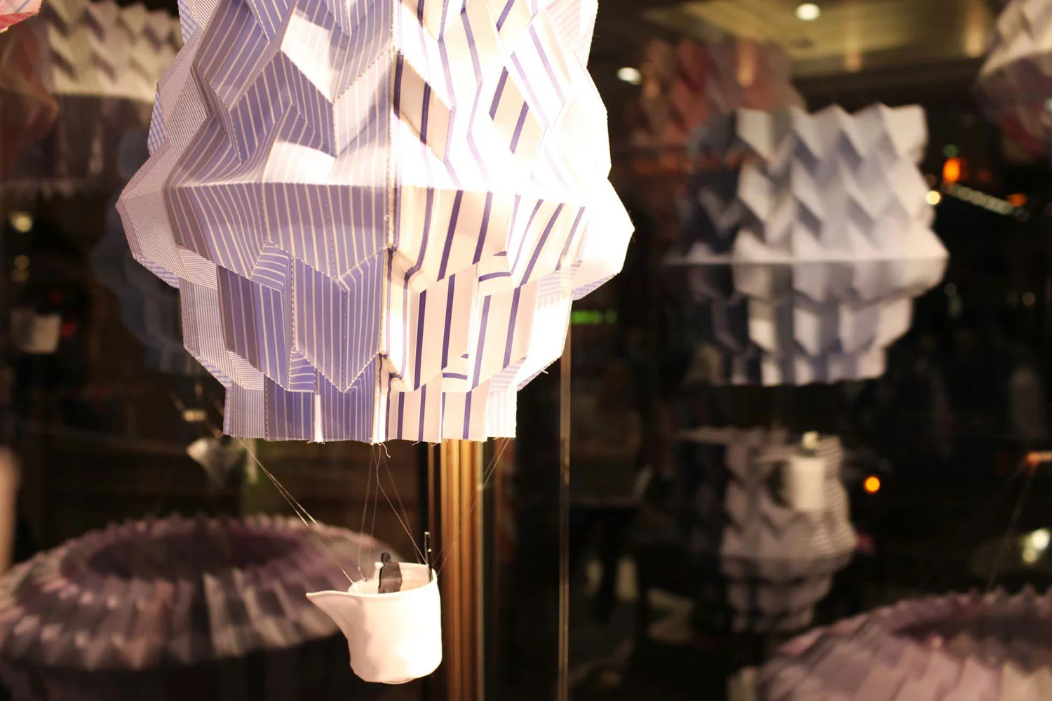 RIBA London hit the shops on Regent Street, London in May 2012 with a new window installation project produced around the theme of ‘PLAY’ in collaboration with the Regent Street Association and media partner ELLE Decoration. We were one of ten architects to be selected to produce a window installation along Regent Street chosen by retailer T.M.Lewin. Our scheme, entitled “High Fliers” mixed the theme of ‘play’ with T.M.Lewin’s brand concept of ‘performance’ where London’s skyline played host to a cluster of serene origami balloons. Using the shirt maker’s crisp folding and cutting techniques, fabrics in multifarious patterns & hues were reshaped into high-flying lanterns. “The Regent Street Windows Project 2012 fuses together cutting-edge architecture from some of the capital’s leading practices and unique retail design. Together, the pieces form a street-wide exhibition open 24/7.” The RIBA Photographed by Tom Gildon