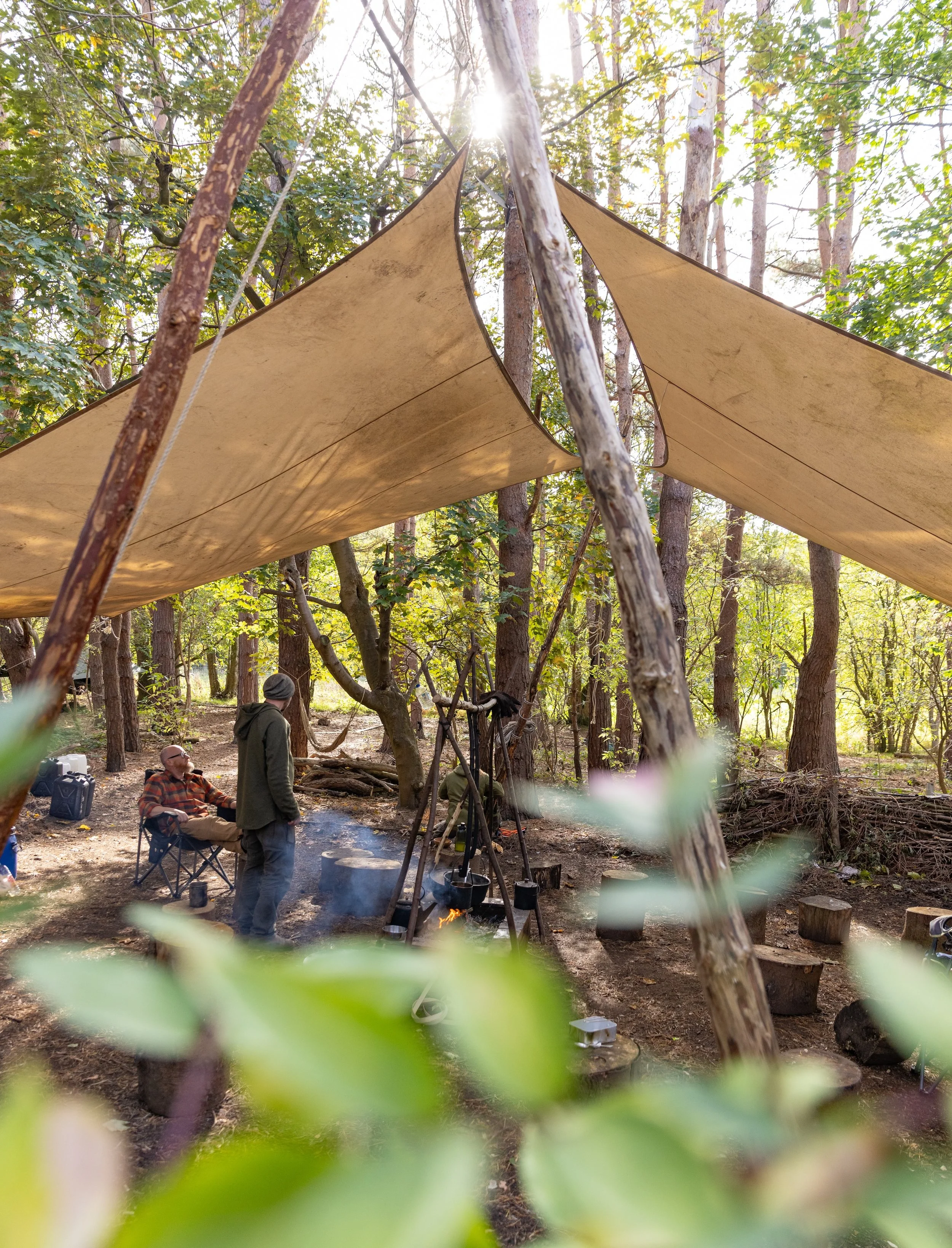 A tent in a wooded area with several people visible inside, enjoying their time together in nature.