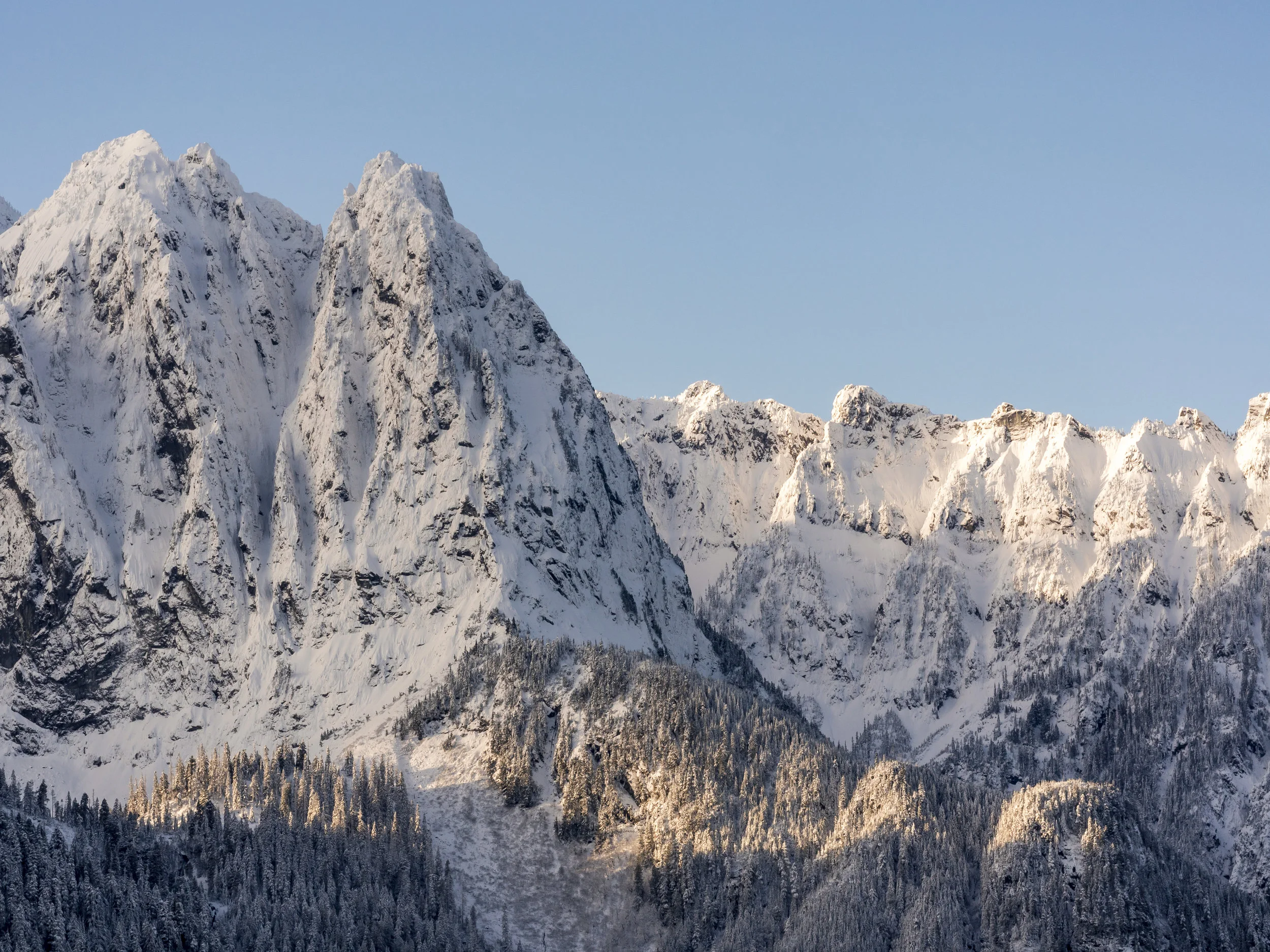 Snow Covered Jagged Peaks with Blue Sky Background in North Cascade Mountain Range