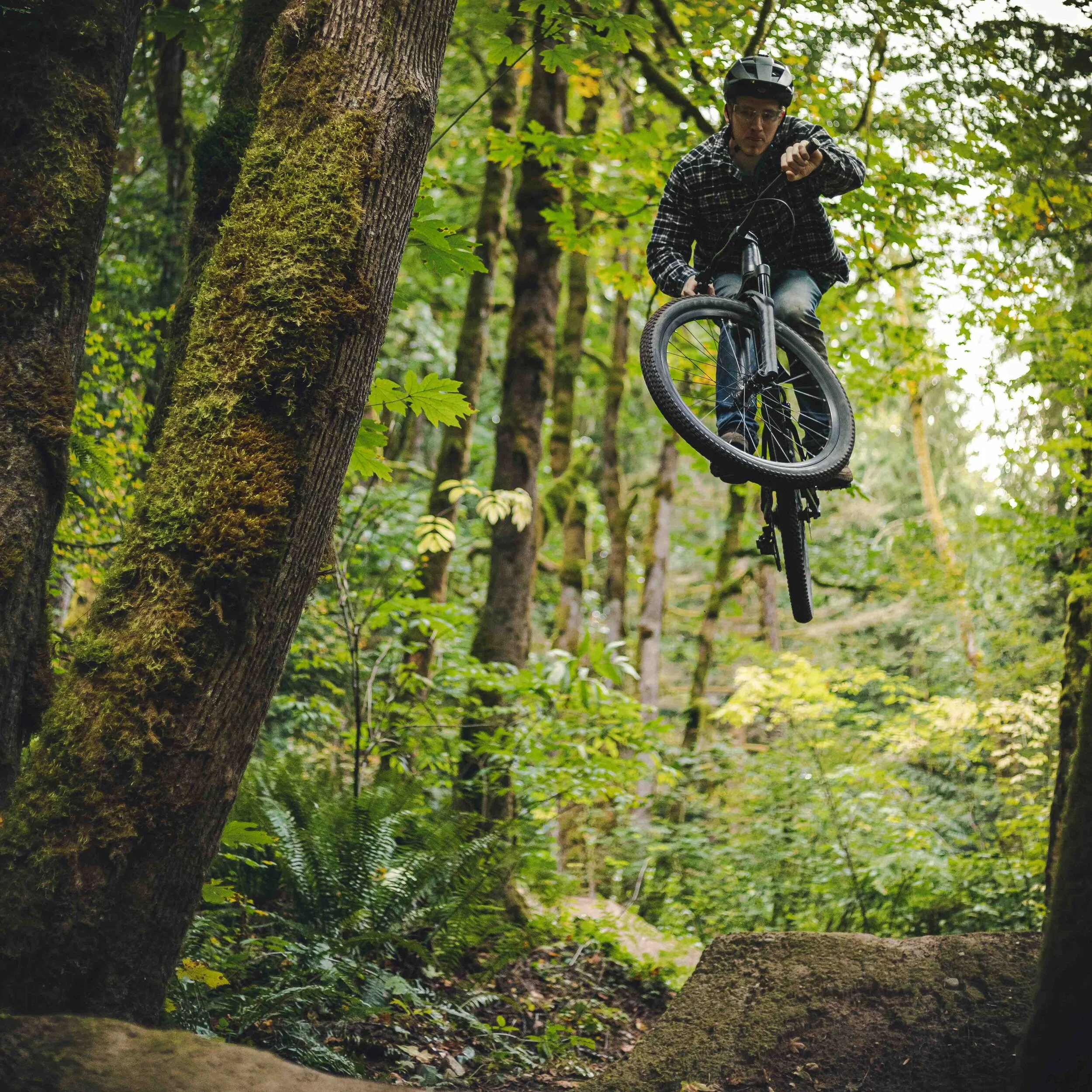 Man_Jumping_High_on_Dirt_Mountain_Bike_Jump_in_the_Woods.jpeg
