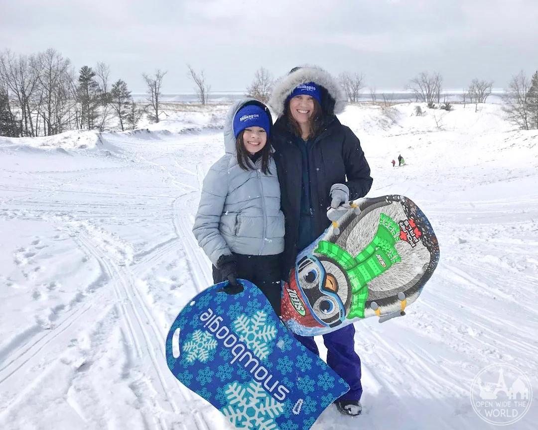 Where to go sledding in Muskegon, Michigan? Sugar Bowl Dune in Muskegon State Park! Near Muskegon Winter Sports Complex. An exciting winter activity in West Michigan. #sledding #openwidetheworld