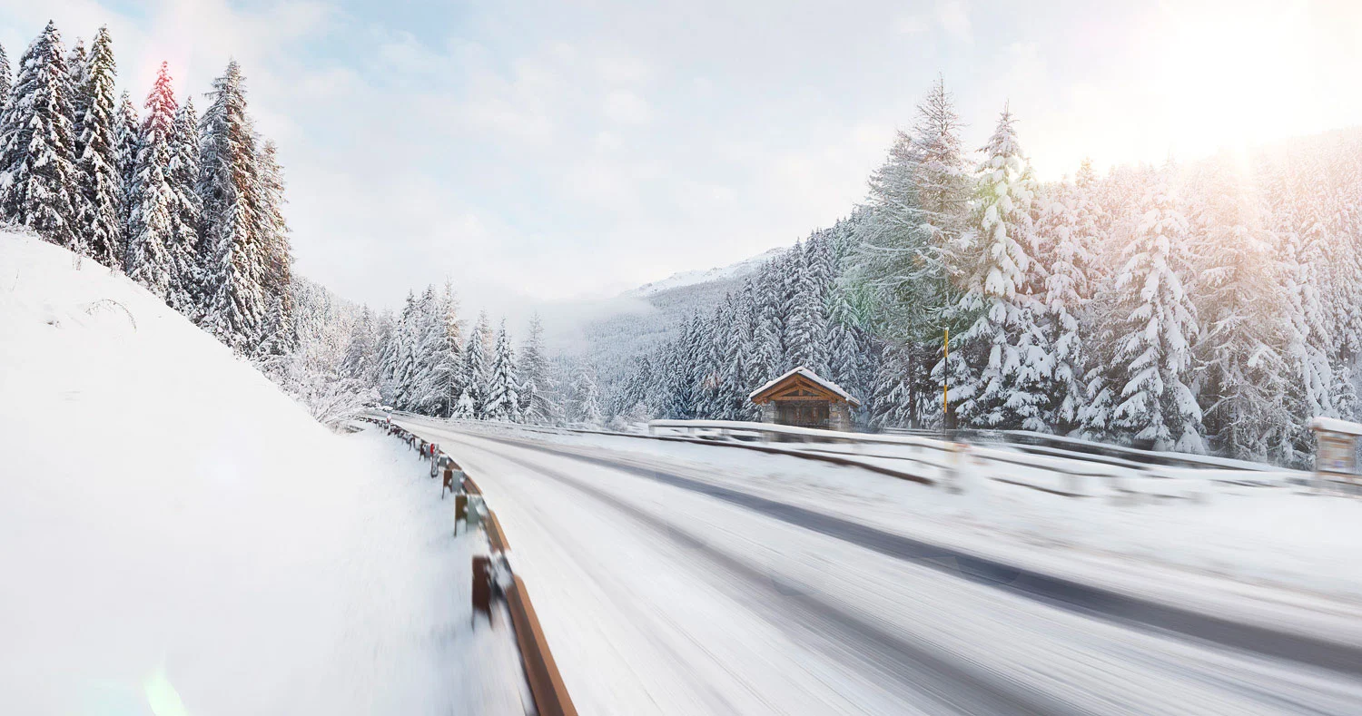 Sun shining on a snow covered road in the mountains of Italy