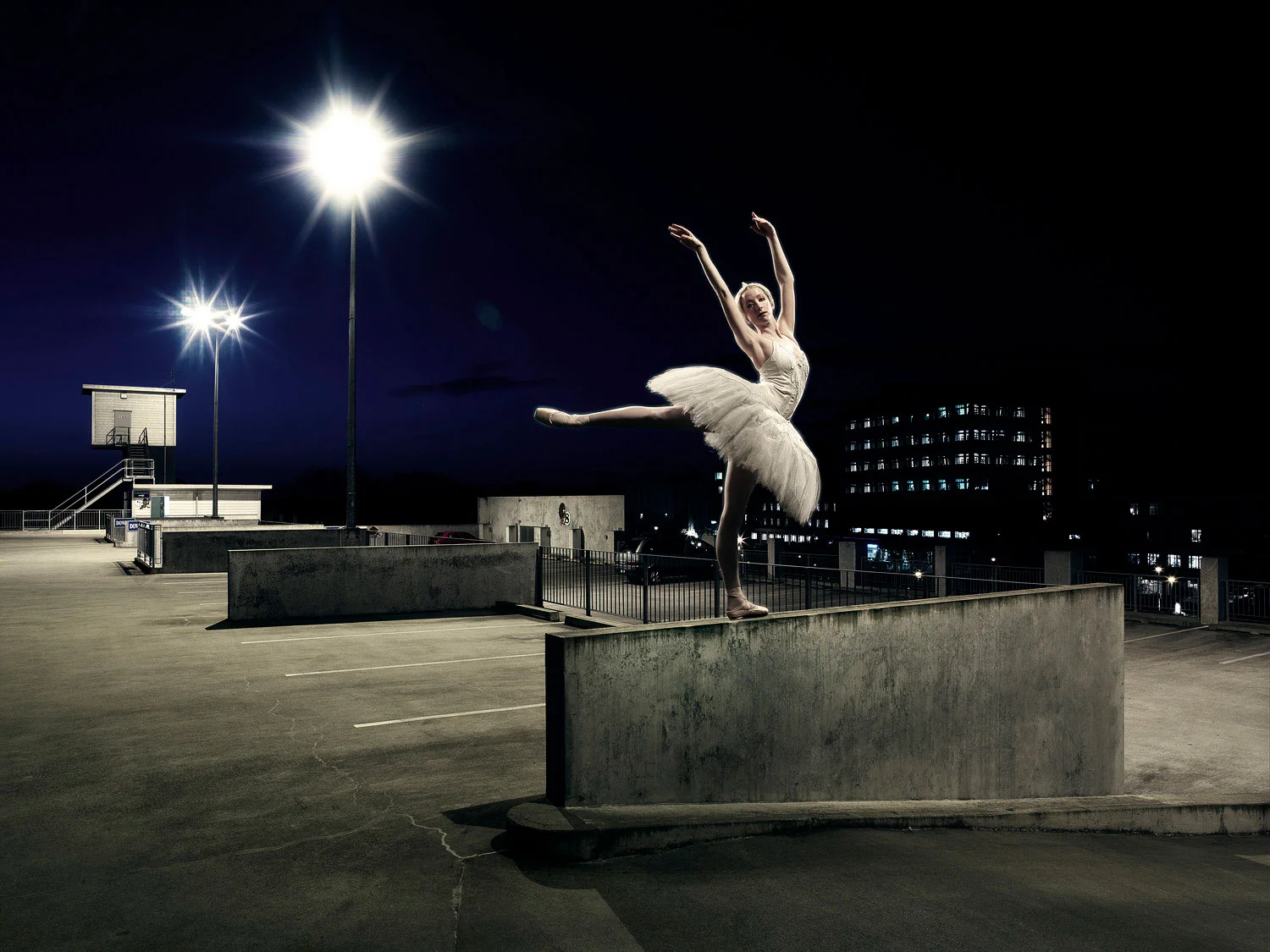 Ballerina dancing on top of a building at night